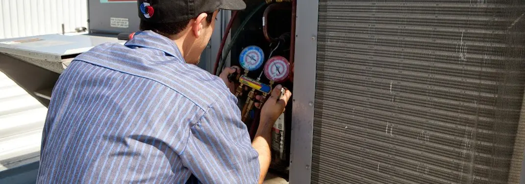 HVAC technician servicing a condenser unit in Pittsfield